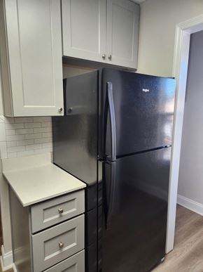 Columbus apartment for rent - A black fridge in a kitchen with white cabinets.