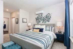 Fairport apartment for rent - a bedroom with a bed and a plant on the wall