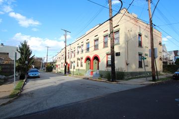 Wilkinsburg apartment for rent - A street view of a building with a blue car parked in front.