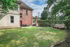 Pittsburgh apartment for rent - A backyard with a wooden bench and a red door.