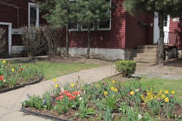 Pittsburgh apartment for rent - A red house with a white door and a small garden in front.