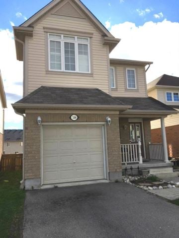 Kitchener house for rent - a yellow house with a white garage door