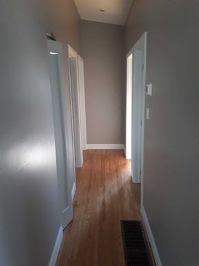 Hamilton house for rent - a hallway with wood floors and grey walls and white doors
