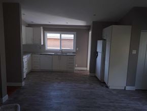 Hamilton house for rent - an empty kitchen with white cabinets and a window