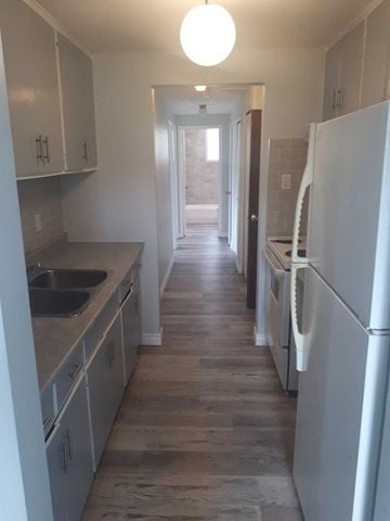 Waterloo apartment for rent - a kitchen with white cabinets and stainless steel appliances and a hallway