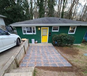 Chapel Hill house for rent - A green house with a yellow door and a white car parked in front.