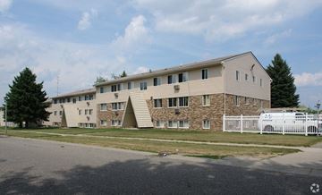 Lansing apartment for rent - A large building with a white picket fence in front.