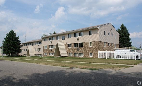 Lansing apartment for rent - A large building with a white picket fence in front.