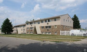Lansing apartment for rent - A large building with a white picket fence in front.