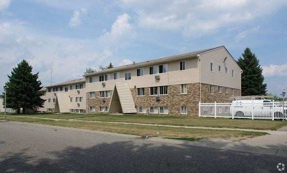 Lansing apartment for rent - A large building with a white picket fence in front.