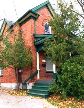 Kitchener apartment for rent - an old red brick house with green stairs