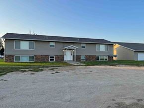 Leonard apartment for rent - A gravel driveway leads to a two-story house with a garage.