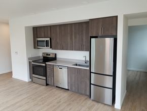 Portland apartment for rent - an empty kitchen with stainless steel appliances and wooden flooring