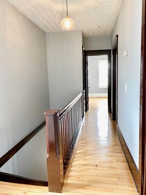 Lakewood house for rent - A hallway with a wooden floor and a light hanging from the ceiling.