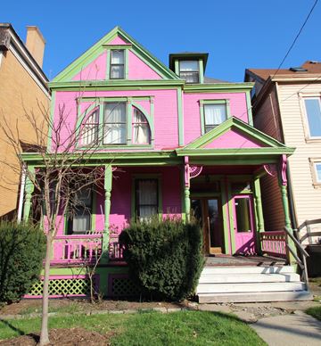 Pittsburgh apartment for rent - A pink house with green trim and a tree in front.