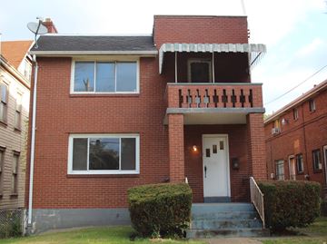Pittsburgh apartment for rent - A red brick house with a white door and windows.