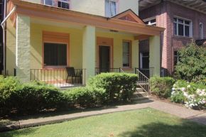 Pittsburgh apartment for rent - a front porch of a yellow house with a lawn and bushes