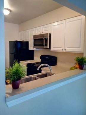 Portland apartment for rent - A kitchen with black and white appliances and white cabinets.
