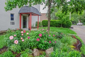 Pittsburgh apartment for rent - A small red and white building with a black roof is surrounded by a garden with pink flowers.