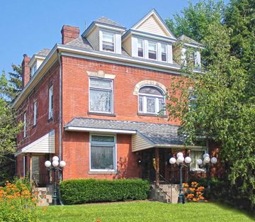 Pittsburgh apartment for rent - a red brick house with a porch and a lawn