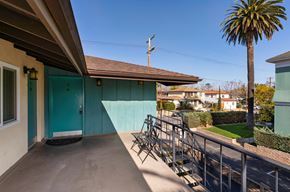 Santa Barbara apartment for rent - a balcony with a blue door and a patio with chairs and a palm tree