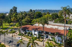 Santa Barbara apartment for rent - A white building with a red roof is surrounded by palm trees.