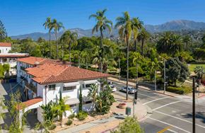 Santa Barbara apartment for rent - A white house with a red roof is surrounded by palm trees.