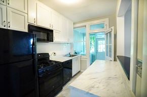 Richmond house for rent - A black fridge and stove in a kitchen with white cabinets.
