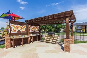 Dallas apartment for rent - A playground with a wooden structure and a colorful umbrella.