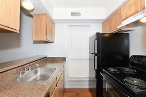Dallas apartment for rent - A black stove top oven sits next to a sink in a kitchen.