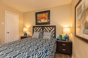 Dallas apartment for rent - A bedroom with a patterned bedspread and two lamps on either side of the bed.