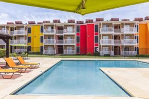 Dallas apartment for rent - A swimming pool is surrounded by sun loungers and chairs.