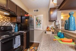 Dallas apartment for rent - A kitchen with black appliances and brown cabinets.