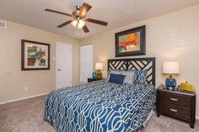 Dallas apartment for rent - A bedroom with a patterned bedspread and a ceiling fan.