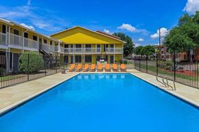 Dallas apartment for rent - A swimming pool in front of a yellow building.