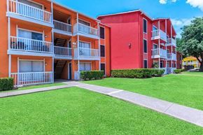 Dallas apartment for rent - A red and orange apartment building with green grass in front.