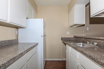 Dallas apartment for rent - A kitchen with white cabinets and a granite countertop.
