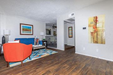 Dallas apartment for rent - A living room with a red chair and a painting on the wall.