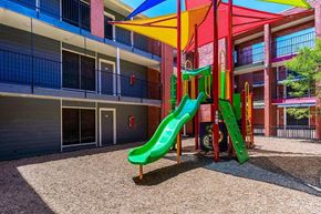 Dallas apartment for rent - A brightly colored playground slide in front of a building.