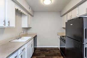 Fort Worth apartment for rent - A kitchen with a black refrigerator and white cabinets.