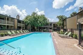 Houston apartment for rent - A swimming pool surrounded by sun loungers and trees.