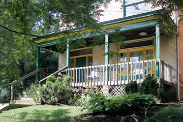 Pittsburgh apartment for rent - A green house with a porch and a yellow window.