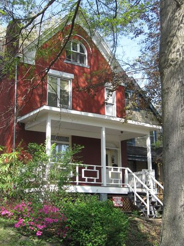 Pittsburgh apartment for rent - A red house with a white porch and a tree in front.