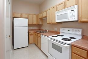 Winona apartment for rent - A kitchen with white appliances and wooden cabinets.