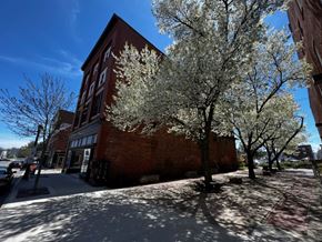 Biddeford apartment for rent - A tree with white blossoms stands in front of a red brick building.