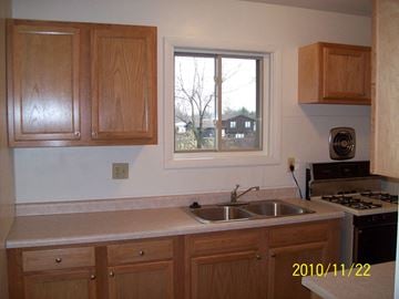 Munster apartment for rent - a kitchen with wooden cabinets and a sink and a window
