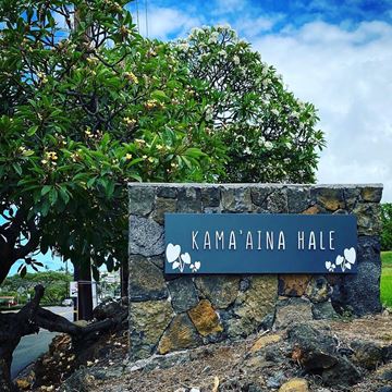 Kailua Kona apartment for rent - A stone wall with a sign that reads "Kama'aina Hale" in front of a tree.