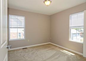 Cumberland apartment for rent - an empty bedroom with two windows and a carpeted floor