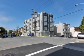 San Francisco apartment for rent - A street view of a residential area with apartment buildings and cars parked on the side of the road.