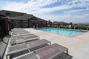 Ankeny apartment for rent - A pool with sun loungers in front of a building.